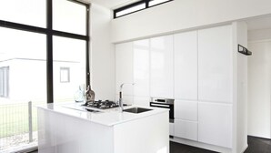 Een moderne keuken met een centraal eiland, witte kasten en een groot raam dat voor natuurlijk licht zorgt.