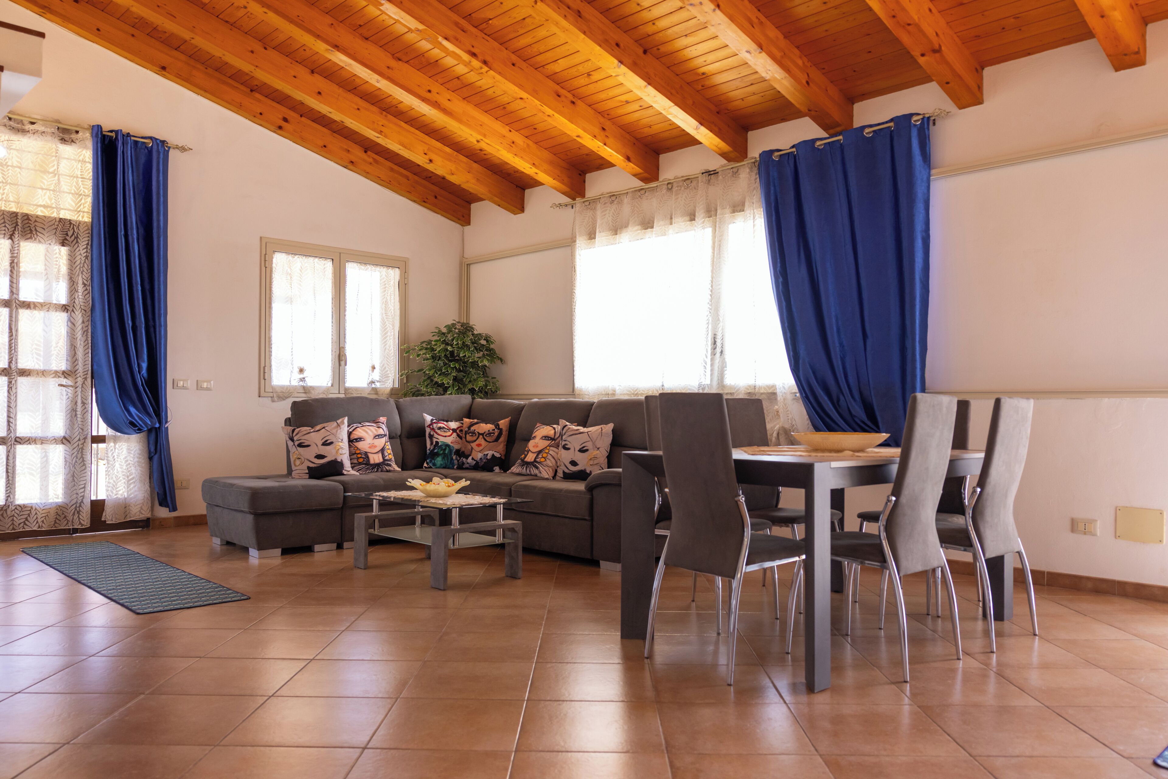 Een woonkamer met een bank, stoelen, een salontafel en een eettafel.