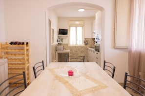 A dining area with a table, chairs, and a wooden rack with bottles.