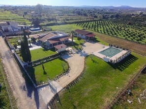 Vista aérea de una propiedad residencial con piscina, cancha de tenis y una casa grande con varias habitaciones.