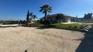 A residential property with a covered patio, a lawn, and a gravel driveway. - Villa Aurelia | Private Pool, 10 Guests, Near the Sea (Sicilia)