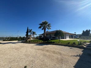 Una propiedad residencial con un patio cubierto, césped y camino de entrada de grava.