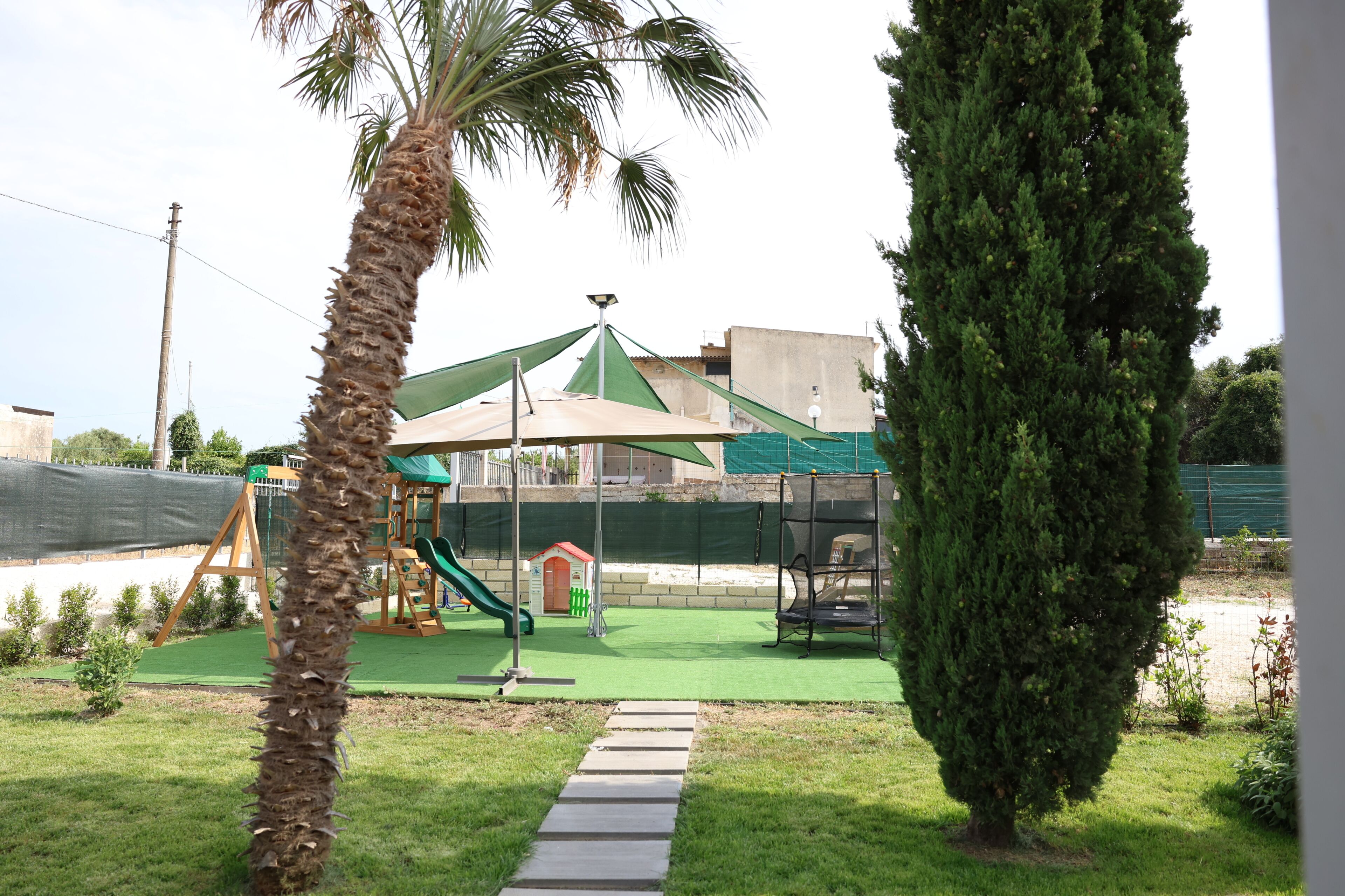 Ein Spielplatz mit Rutsche, Schaukeln und einer kleinen Spielhaus-Konstruktion.
