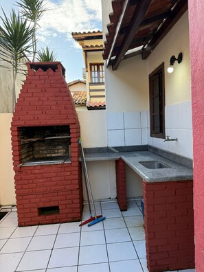 A brick-built outdoor kitchen with a chimney, a tiled floor, and a window. - Nazareth ap 17 (Porto Seguro)