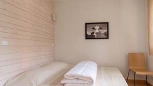 Ein Zimmer mit einem Bett, einem Sessel, einem Wandbild und einer Holzwand.