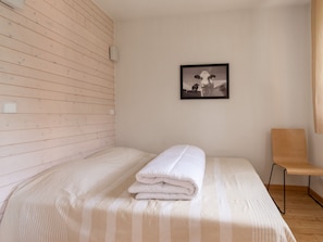 Ein Zimmer mit einem Bett, einem Sessel, einem Wandbild und einer Holzwand.
