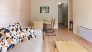 Ein modernes Zimmer mit einer Couch, einem Esstisch und Stühlen. An der Wand hängt ein gerahmtes Bild.