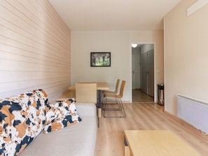 Ein modernes Zimmer mit einer Couch, einem Esstisch und Stühlen. An der Wand hängt ein gerahmtes Bild.