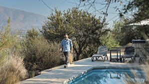 A pool area with lounge chairs, a person walking, and surrounding vegetation. - Villa Fiesole 2-bedroom farmhouse in welcoming Limache perfect for relaxing (Limache)