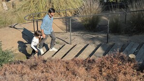 A person descending a wooden staircase with metal railings, surrounded by dry grass and bushes. - Villa Fiesole 2-bedroom farmhouse in welcoming Limache perfect for relaxing (Limache)