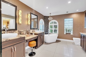 Un baño moderno con una bañera grande, dos lavamanos, un tocador y un taburete.