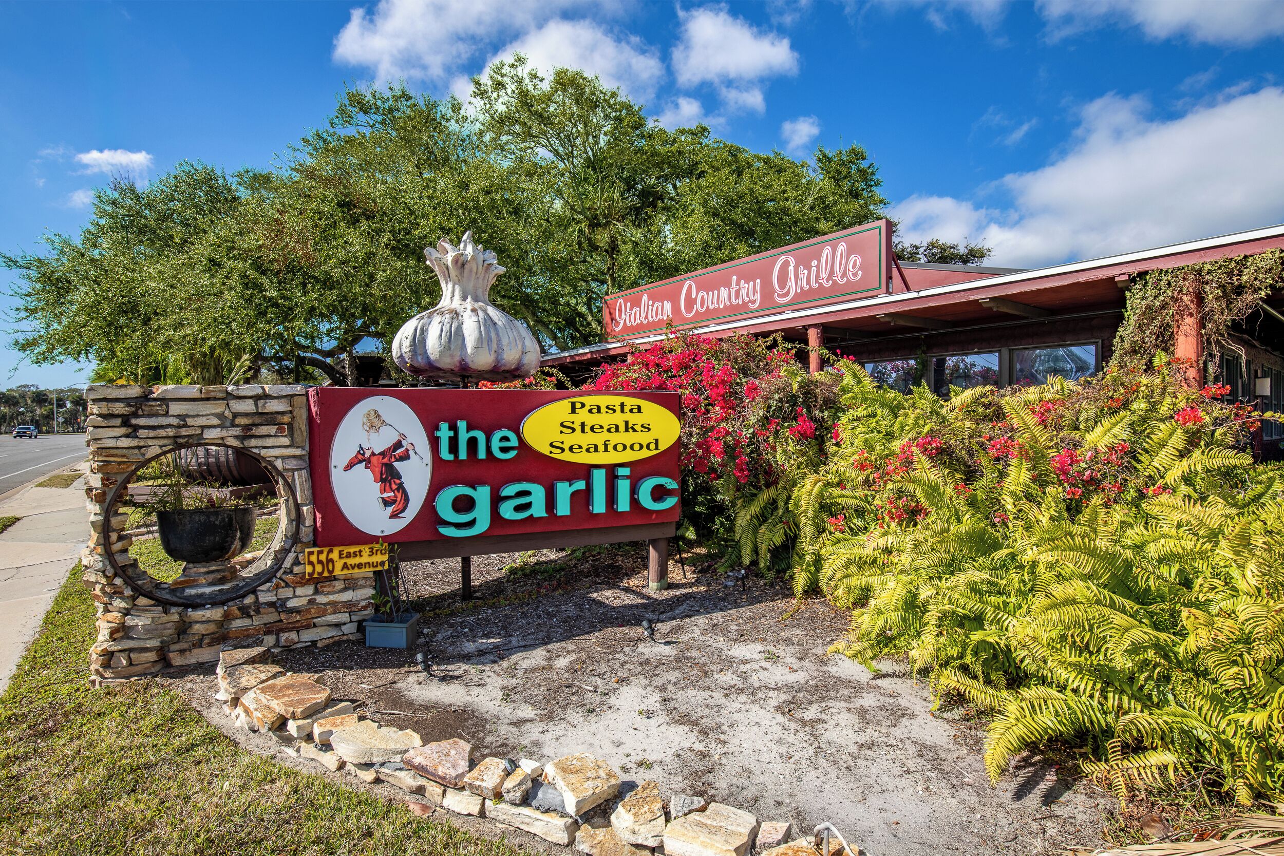 En restaurantskilt med teksten 'The Garlic' og 'Pasta, Steaks, Seafood'.