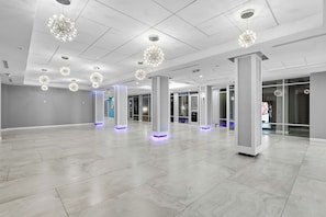 A spacious, modern lobby with a high ceiling, geometric chandeliers, and a polished tile floor. - 🌴Amazing Ocean Views | Beachfront Pool | Oceanside Inn 606🌴 (Daytona Beach)