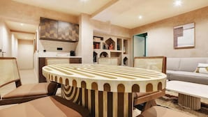 Ein modernes Wohnzimmer mit rundem Tisch, gepolsterten Sesseln, einer Couch und einer Küchenzeile mit Einbauschränken.