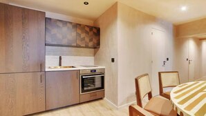 Eine moderne Küche mit Holzausbau, einem eingebauten Ofen und einem Essbereich mit gestreifter Tischdecke.