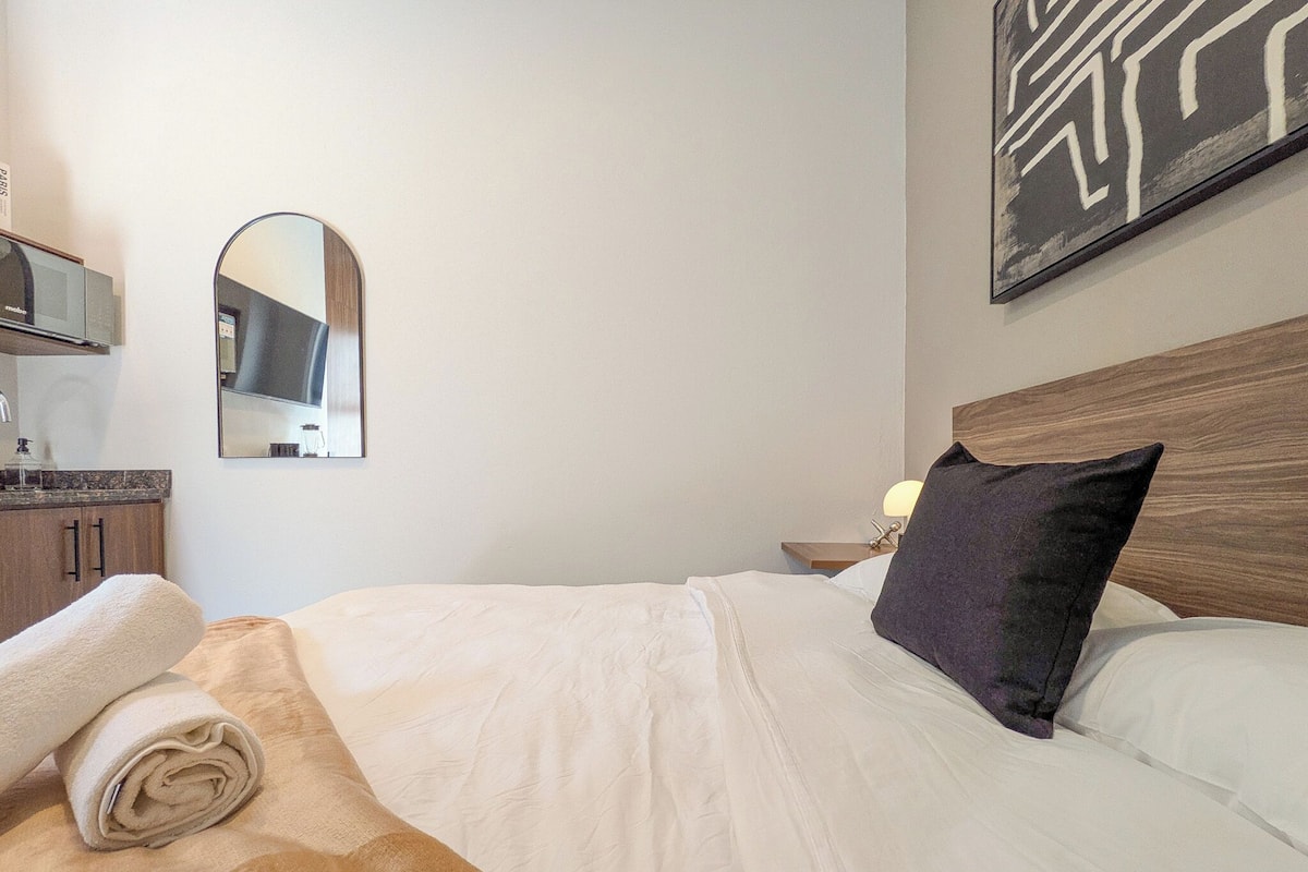 Une chambre d’hôtel avec un lit, une table de chevet, un miroir et un tableau au mur.