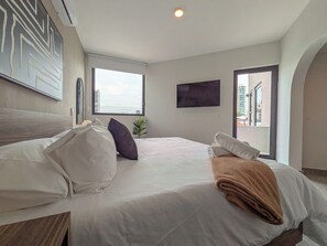 A hotel room with a bed, a TV, a window, and a view of the city. - Casa Heredia (Guadalajara)