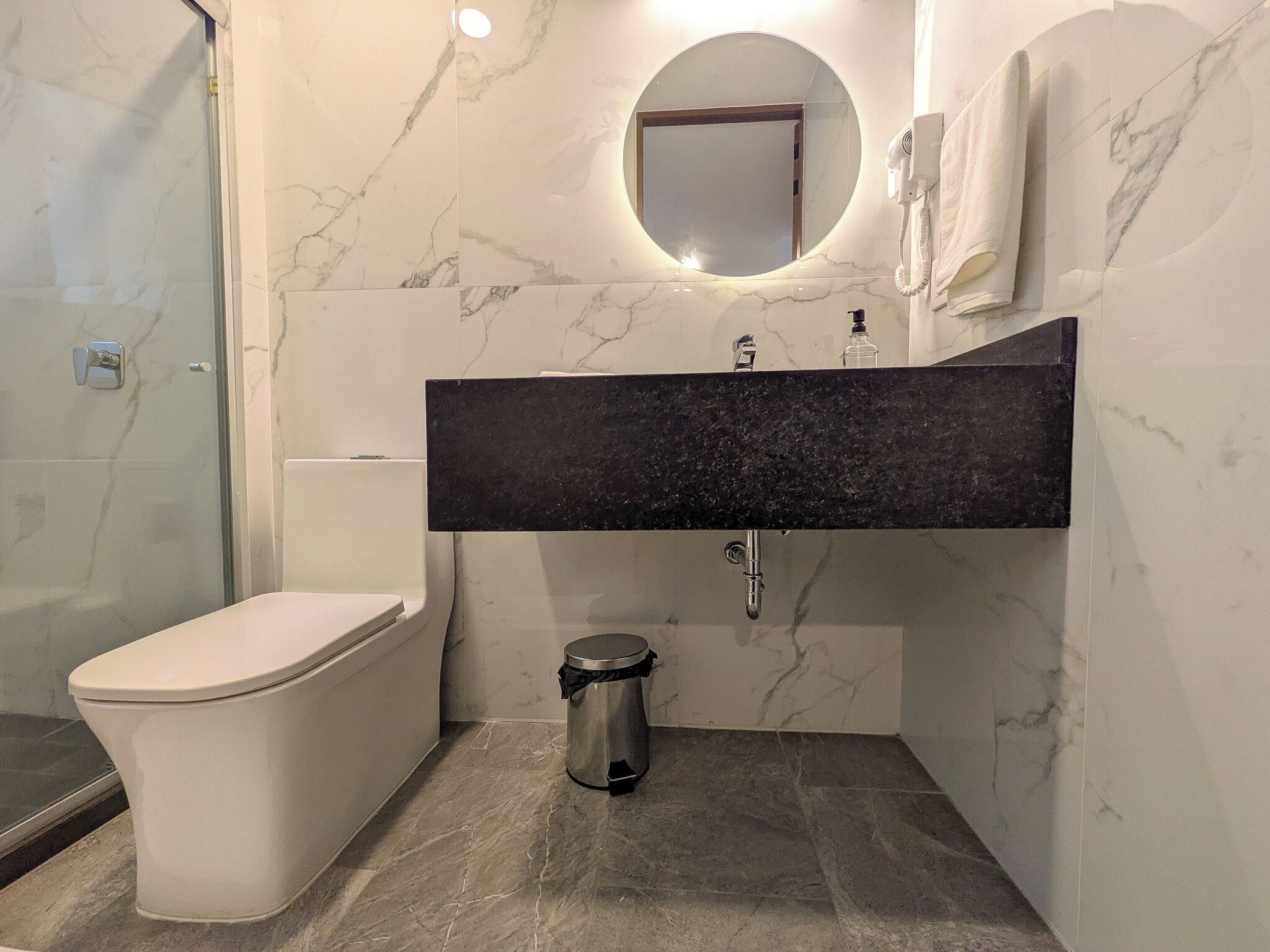 Un bagno moderno con toilette, lavandino e specchio.