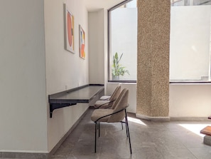 A modern bathroom with a bathtub, a towel rack, and a window with a view of a building. - Casa Heredia (Guadalajara)