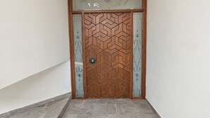 Una puerta de madera con diseños geométricos y un panel de vidrio decorativo en la parte superior.
