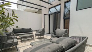 Un área de estar al aire libre moderna con mobiliario de mimbre y techo de vidrio.