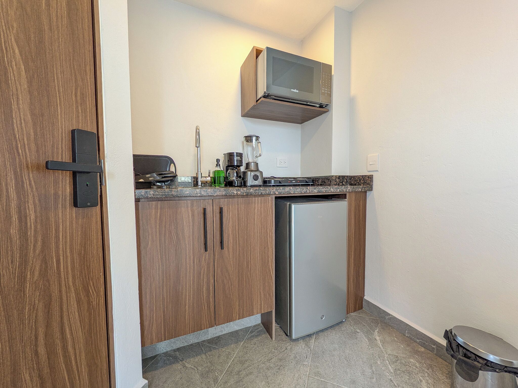 A compact kitchen with a built-in microwave, a coffee maker, and a dishwasher.