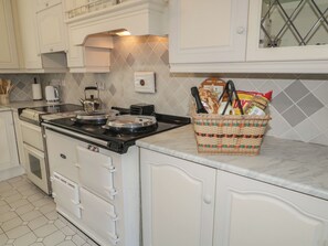 A kitchen with white cabinets, a stove, a toaster, and a wicker basket on the countertop.