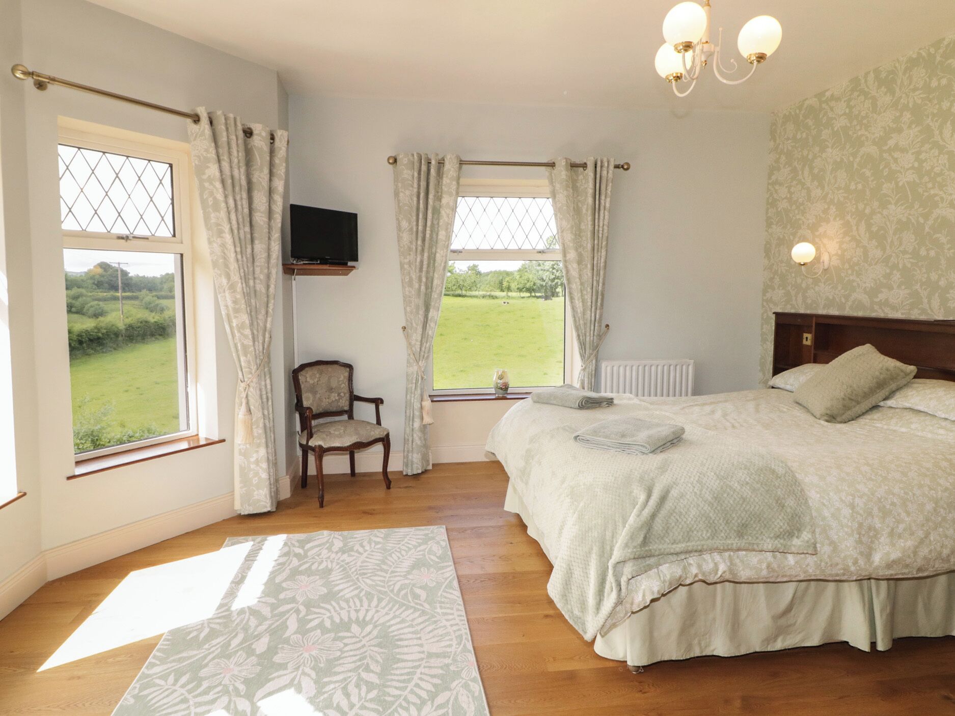 Een slaapkamer met een bed, een stoel, een televisie en uitzicht op de omgeving.