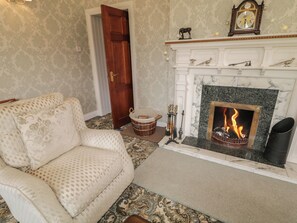 Una sala de estar con chimenea, un sofá, un tapete estampado y una puerta.