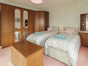 A bedroom with two beds, a wooden dresser, and a wardrobe.