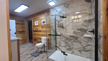 A modern bathroom with a glass shower enclosure, a toilet, and wooden paneling.