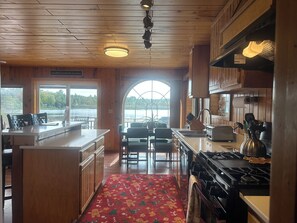 A cabin interior with a kitchen, dining area, and a large window overlooking a lake. - Hot tub*beautiful views*lakefront*close to PRNL (Christmas)
