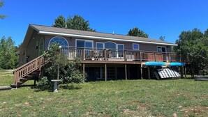 A two-story house with a deck, large windows, and a covered outdoor area. - Hot tub*beautiful views*lakefront*close to PRNL (Christmas)