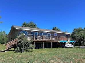 A two-story house with a deck, large windows, and a covered outdoor area.