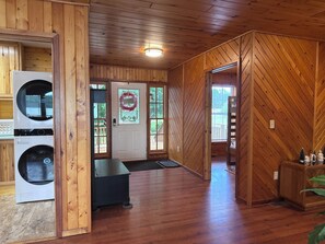 A laundry room with stacked washers and dryers, a bench, and a door with a wreath. - Hot tub*beautiful views*lakefront*close to PRNL (Christmas)