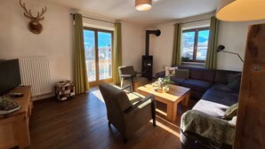 A living room with a fireplace, a sofa, a coffee table, and a television. - Chalet With Mountain View (Piesendorf)