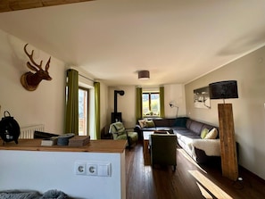 Ein gemütliches Wohnzimmer mit Kamin, einer Couch, einem Couchtisch und einem aufgehängten Hirschgeweih.