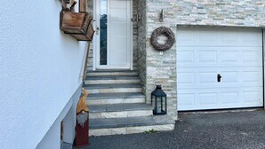 A house with a stone facade, a white garage door, and a wooden staircase leading to the entrance. - Chalet With Mountain View (Piesendorf)