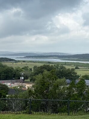 Vista de uma paisagem costeira com estrada, árvores e um corpo d'água ao longe.