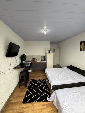 A room with two beds, a desk with a computer, a microwave, and a small kitchenette. - Comfortable apartment in Caieras, 20 minutes from the capital of São Paulo. (Caieiras)