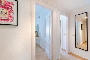 Ein Flur mit einem gerahmten Poster, einem Spiegel und einer zur Toilette führenden Tür.