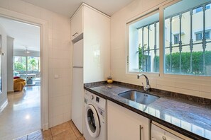 Eine moderne Küche mit integriertem Waschmaschine, einer Spüle und einem Fenster mit Blick auf Grünflächen.