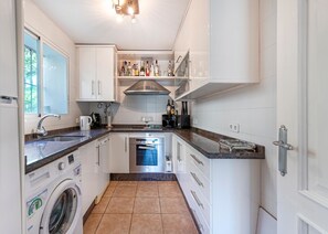 Eine kompakte Küche mit Waschmaschine, Backofen und integriertem Weinregal.