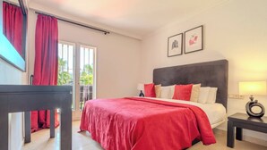 A bedroom with a bed, a nightstand, a lamp, and a window with curtains. - Lalq13 Stunning Frontline Golf 3 bed apt (Benahavis)