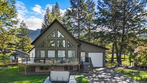 A two-story house with a deck, a garage, and a large window. - Evercrest A-Frame | Hot Tub | Pool Tbl | Fireplace (Radium Hot Springs)