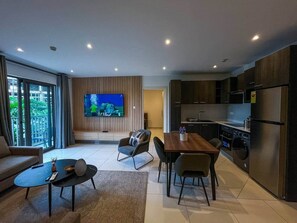 Ein modernes Wohnzimmer mit Fernseher, Sofa, Couchtisch und Essbereich.