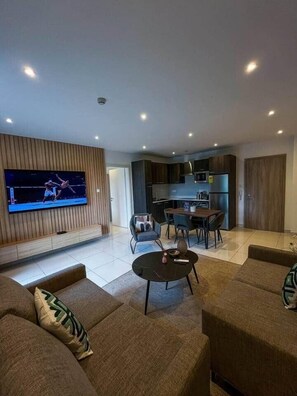 Ein modernes Wohnzimmer mit Flachbildfernseher, Essbereich und Küche.