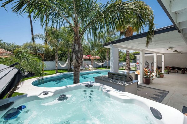 Ein Garten mit Whirlpool, Pool und überdachter Terrasse.