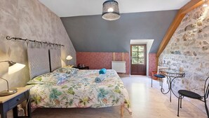 A bedroom with a bed, bedside table, lamp, and a stone wall.