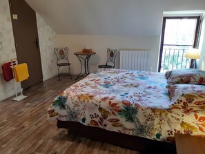 Une chambre à coucher comprenant un lit, deux chaises, une petite table, un radiateur et une fenêtre donnant sur un paysage agréable.